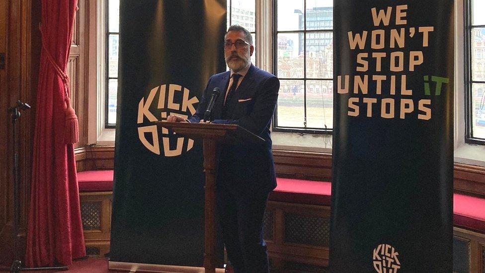 Sanjay Bhandari giving a talk in front of branded Kick It Out Pull up banners.