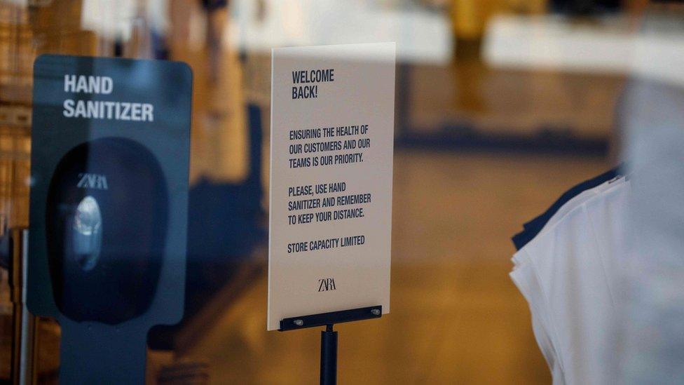 A sign welcoming back the customers is seen next to a hand sanitizer station inside a closed Zara shop