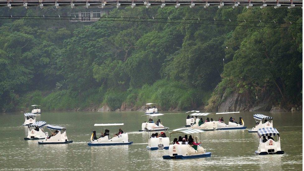 Tourists sail boats in Pitan, a popular area in Xindian district in New Taipei City on September 27, 2015 as typhoon Dujuan approaches the northeast of Taiwan.