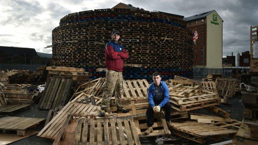 Douglas (L) and Darren McDowell (R) pose with their creation as work continues on the Sandy Row bonfire on July 10, 2017 in Belfast, Northern Ireland.