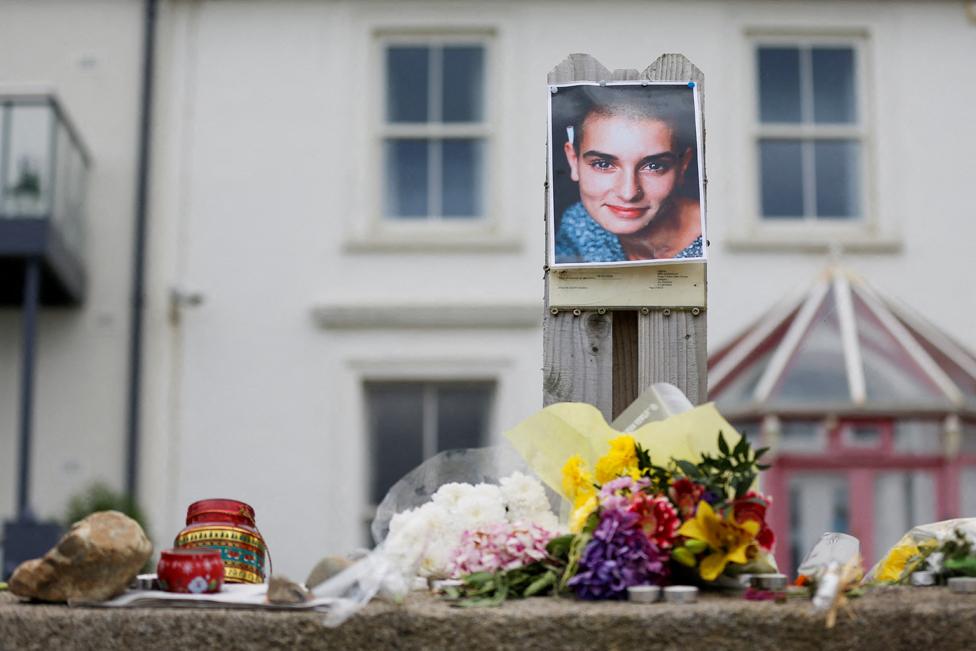 A picture of late singer Sinead O'Connor and floral tributes outside her former Irish home, in the seaside town of Bray in County Wicklow, Ireland, July 27, 2023.