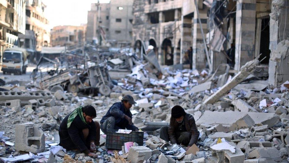 Syrians pick amongst the debris around the bombed out remains of a local council building hit in an airstrike carried out by forces allied with the al-Assad regime on opposition held Douma, outskirts of Damascus, Syria, 30 December 2015