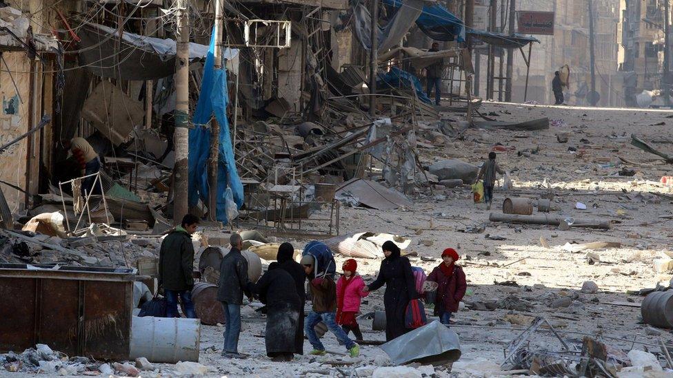 Syrians walk over rubble of damaged buildings, while carrying their belongings, as they flee clashes between government forces and rebels in Tariq al-Bab and al-Sakhour neighbourhoods of eastern Aleppo towards other rebel held besieged areas of Aleppo