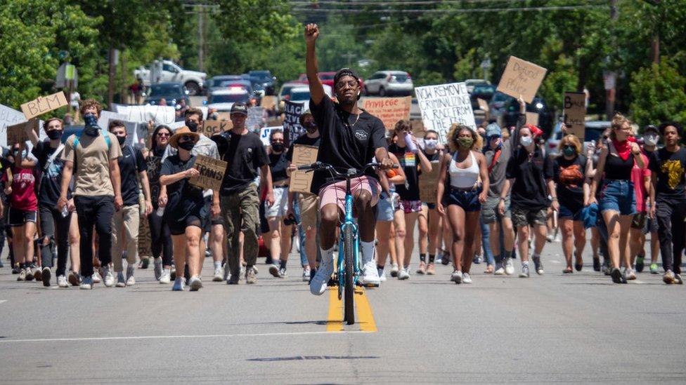 Demonstrators raise signs in the air during as they march in protest for the 15th straight day over the death of George Floyd