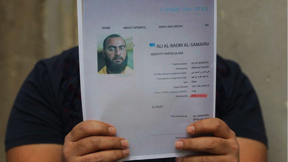 An Iraqi man holds printed profiles of Abu Bakr al-Baghdadi released by Iraqi authorities on 6 February 2018