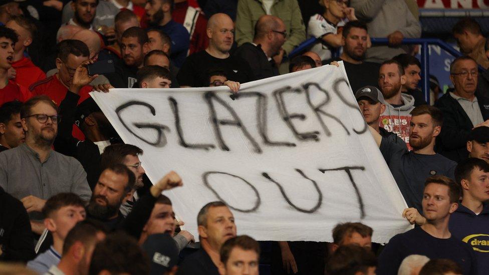 Manchester United fans display banners in protest of the Glazer family’s ownership of the club inside the stadium