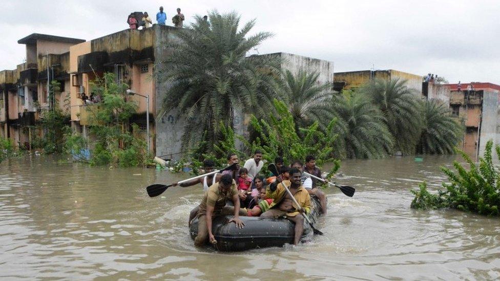 Indian rescue personnel and police officials paddle an inflatable boat through floodwaters as they evacuate residents in Chennai on December 2, 2015