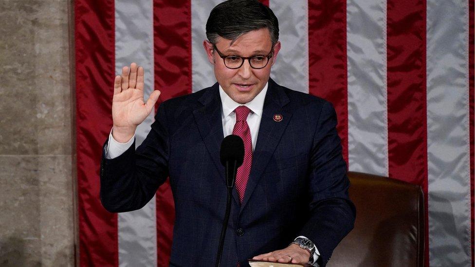 Mike Wendling in front of American flag with hand up