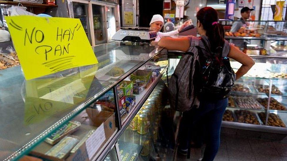 A woman waits at a bakery displaying a sign reading "No Bread", in Caracas on 25 February 2016