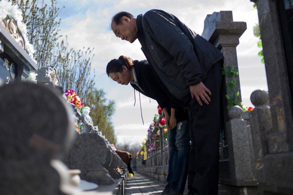 Family members bow at a grave on April 1, 2017, ahead of the annual Qingming festival, or Tomb Sweeping Day, at a cemetary in Dagantangcun, 30km east of Beijing