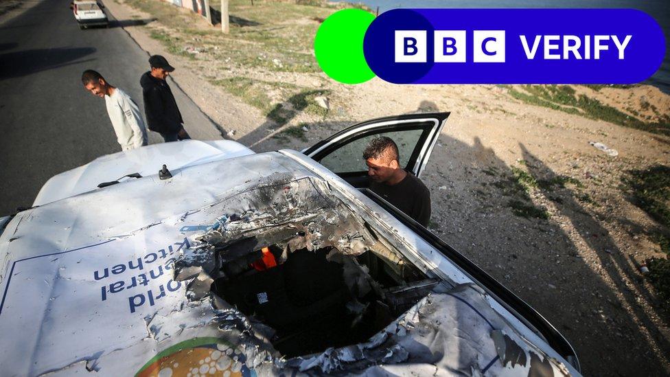 Car with a jagged hole in its roof. The logo of the World Central Kitchen can also be seen.