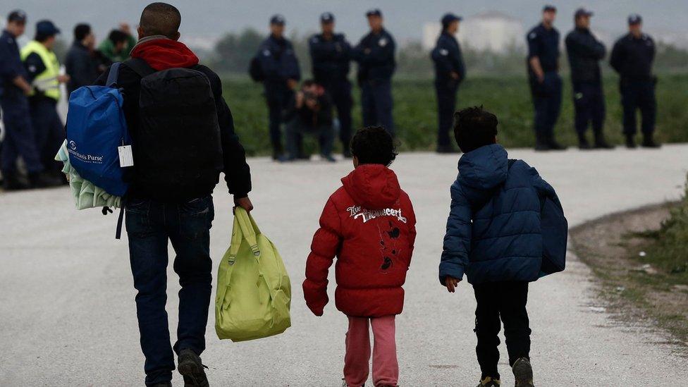 Migrants carry their belongings as they leave Idomeni camp, Greece, on 24 May 2016