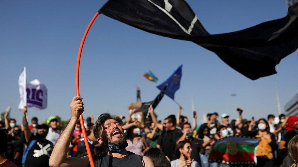 A man waves a flag as demonstrators congregate after Lucia Hiriart, the widow of Former Chilean dictator Augusto Pinochet, passed away, in Santiago