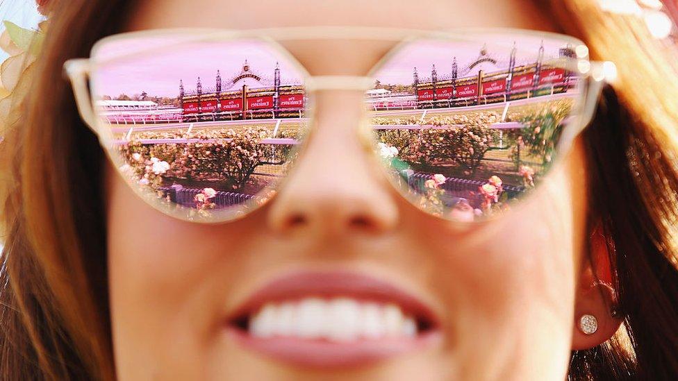 The winning post reflected in a race-goer's sunglasses