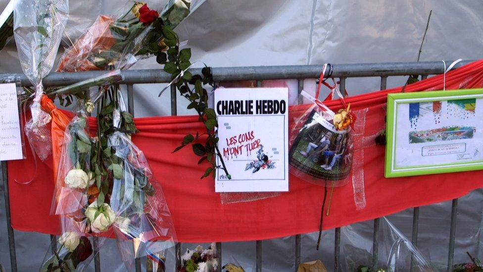 Memorial outside Bataclan venue with flowers and a banner about Charlie Hebdo