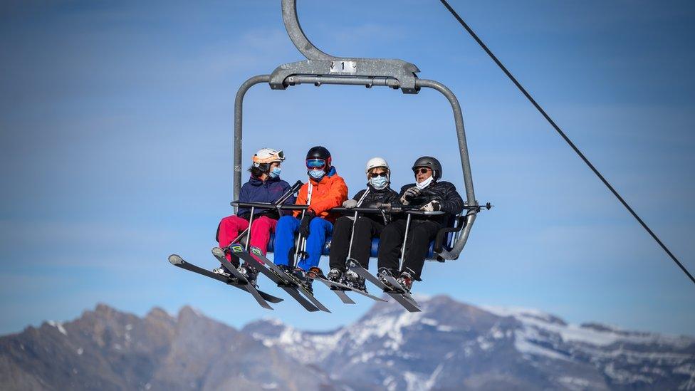 Skiers wearing protective face masks against the spread of the Covid-19, caused by the novel coronavirus, rides a ski lift before hitting the slopes in the Swiss ski resort of Verbier