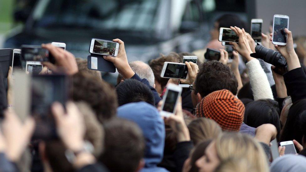 Students and memories of the public hold their camera phones aloft