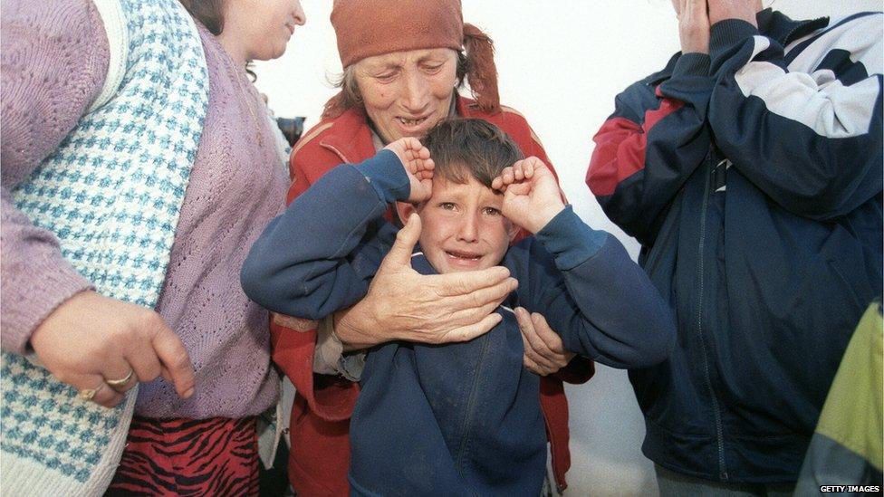 A picture taken on March 7, 1998 shows an elderly ethnic Albanian refugee woman from the village of Donje Prekaze crying as she holds her grandson while hiding from Serbian police in a house in the forest near their village