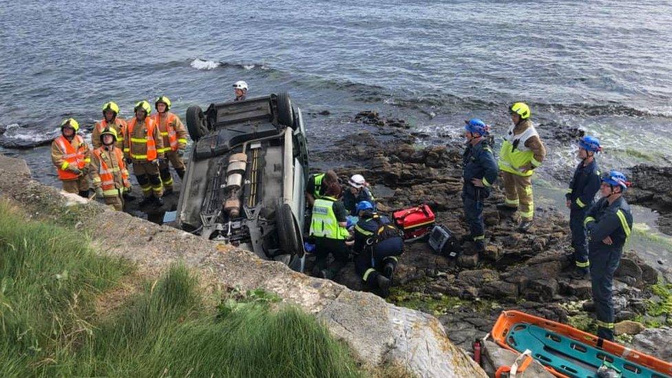 Vehicle on its roof attended by members of the coastguard, fire service and paramedics