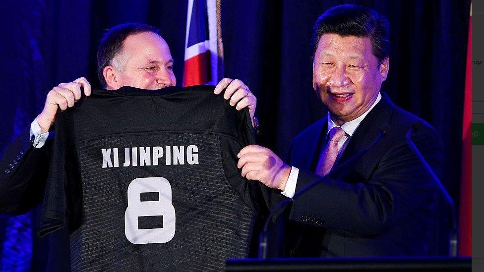 Prime Minister John Key of New Zealand presents President Xi Jinping of China with a personalised All Blacks rugby jersey in 2014