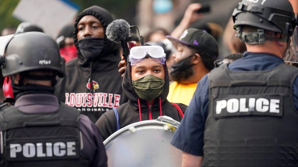 Police stand guard as people react after a decision in the criminal case against police officers involved in the death of Breonna Taylor