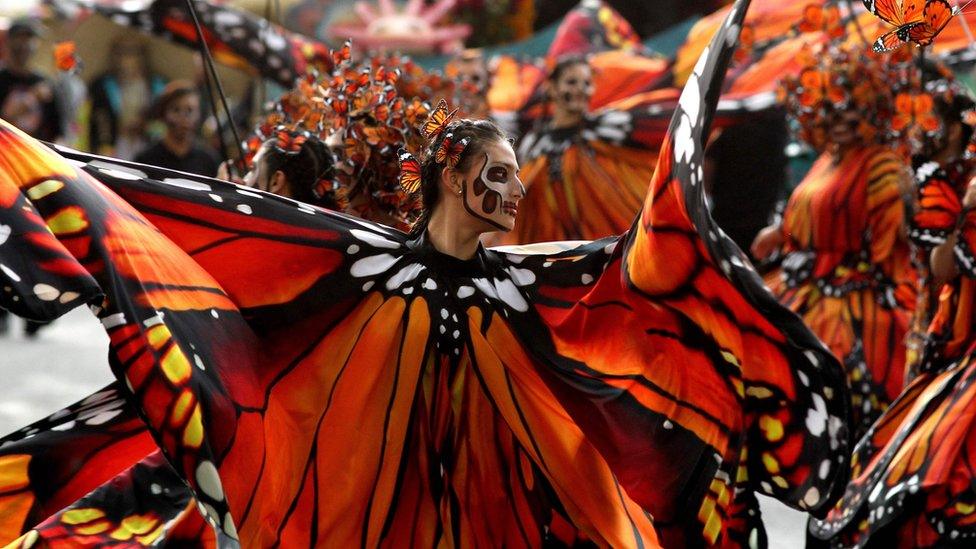 Women dressed as butterflies dance during the parade