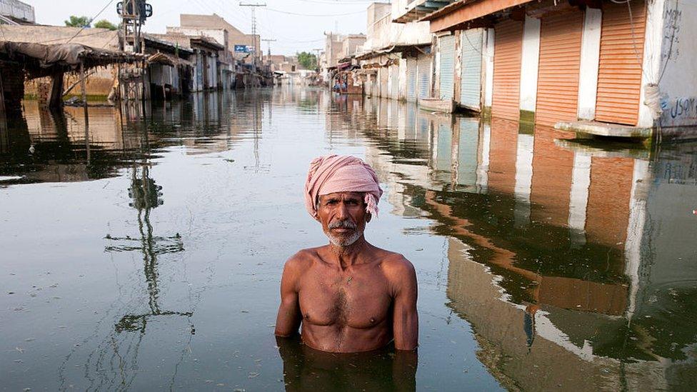 A man wearing a pink turban stands in the centre of Khairpur Nathan Shah town in Pakistan, which has been totally submerged by floodwaters.