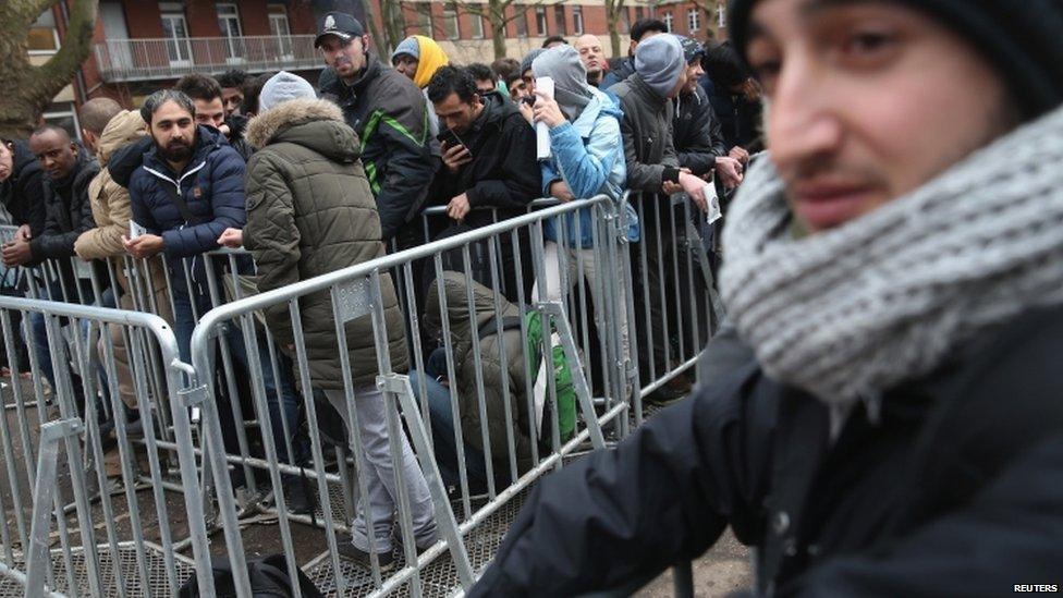 Asylum applicants wait outside the the Central Registration Office for Asylum Seekers