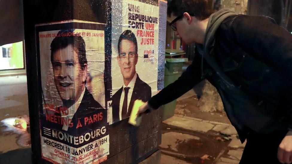 A supporter of Manuel Valls puts up a campaign poster in Paris (11 Jan)