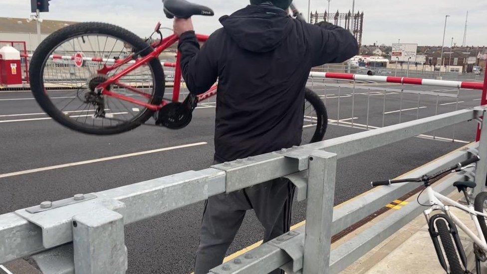 Man lifting his bike over a barrier