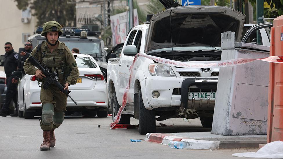 An Israeli soldier stands guard next to a pickup truck mounted with machine gun in the southern city of Sderot on October 7, 2023