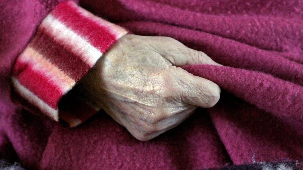 Older person holding onto her housecoat