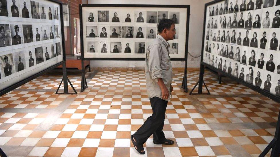 A man looks at photographs of victims at the Tuol Sleng genocide museum in Phnom Penh