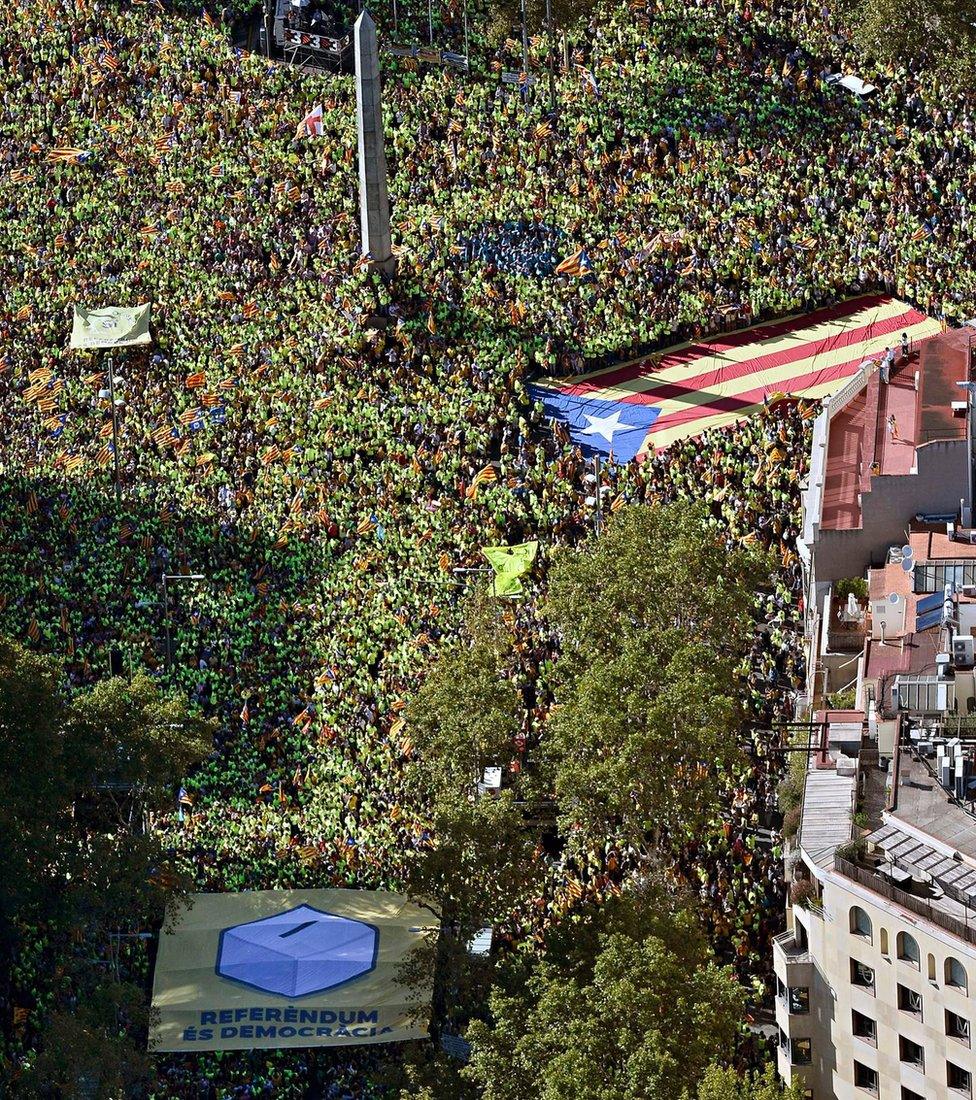 An aerial view of people waving a giant "Estelada" (pro-independence Catalan flags) and a giant banner reading in Catalan "Peace" during a pro-independence demonstration, on September 11, 2017