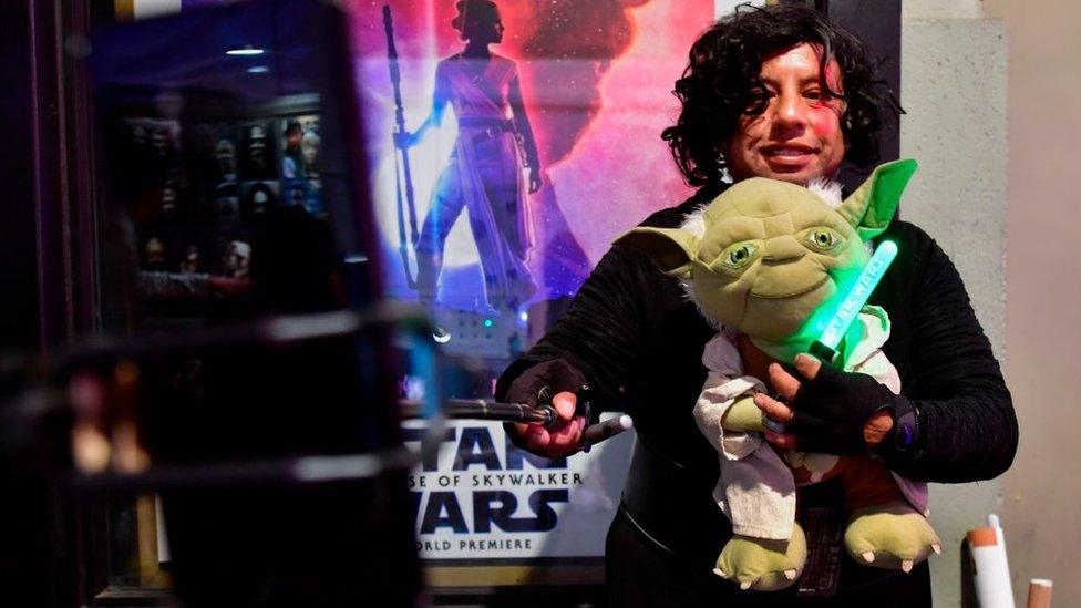 a-fan-with-a-yoda-toy-at-star-wars-premiere.