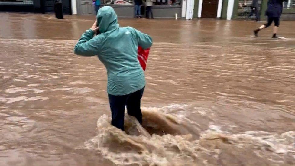 A screengrab from video showing a woman walking through floods in Midletown