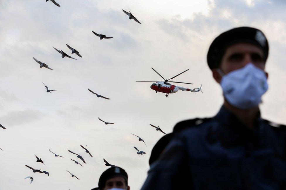 A police helicopter is seen flying over police officials wearing face masks.