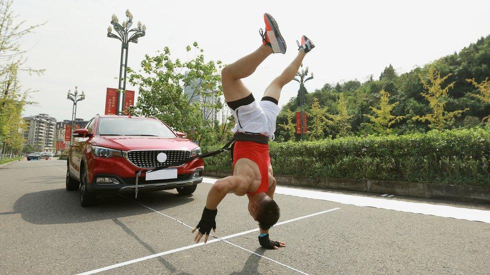 Man pulling car walking on hands