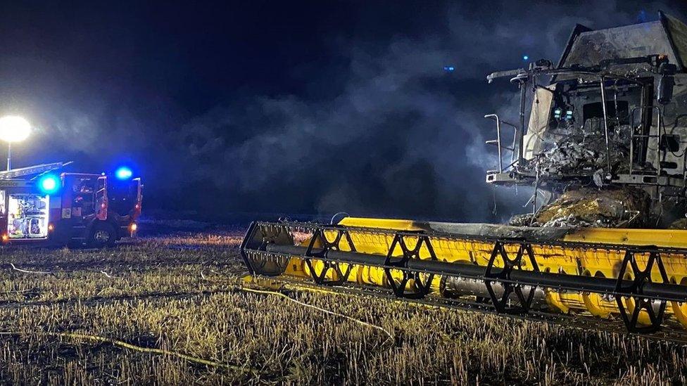 Combine harvester next to a fire truck in a field