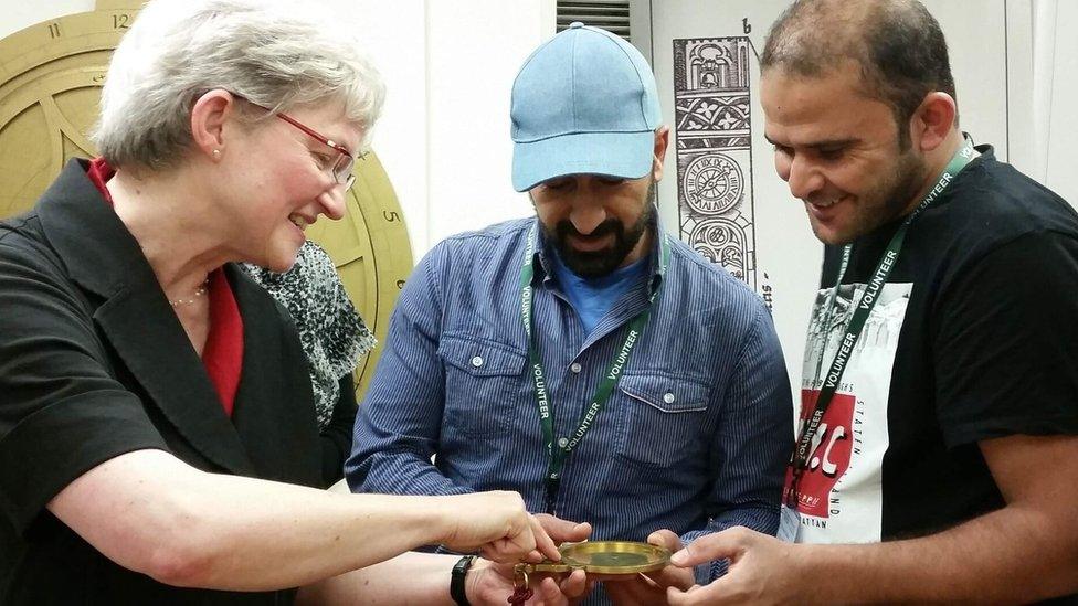 Volunteers Tammam and Abdullah examine an astrolabe with museum director Silke Ackermann