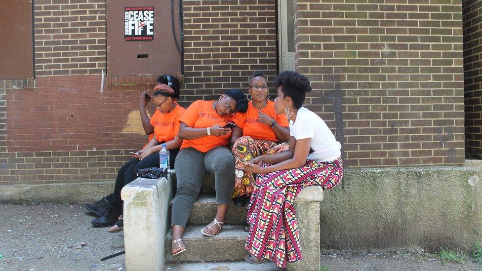 Erricka Bridgeford, right centre, sits with her friend Ellen Gee, right, and her children outside of an abandoned rowhouse