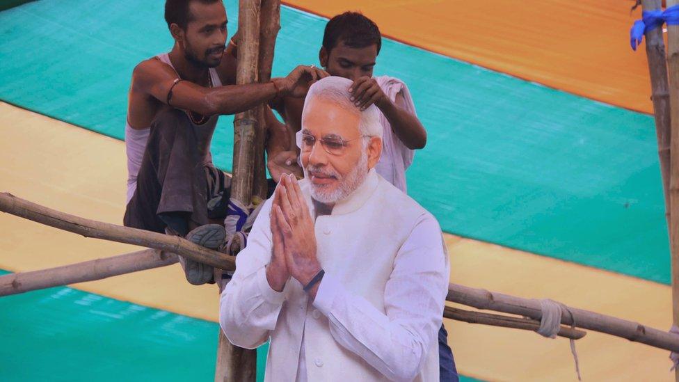 Bharatiya Janata Party (BJP) supporters hold a cut-out of Indian prime minister Narendra Modi as Modi addresses the 'Parivartan' rally in Gaya on August 9, 2015.