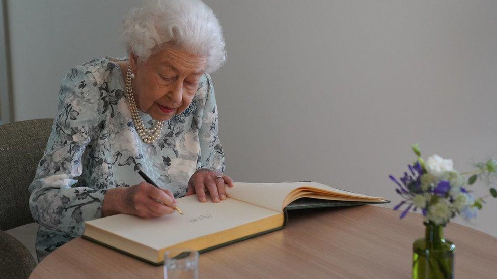 Queen signs visitors book