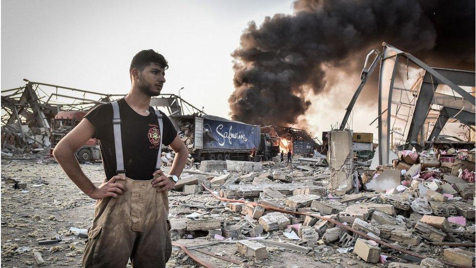 Rescue worker stands amid debris in aftermath of blast