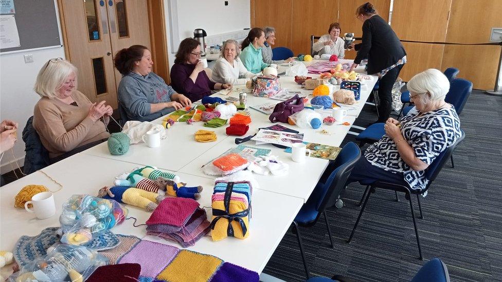 Group of women sitting around a table doing crochet