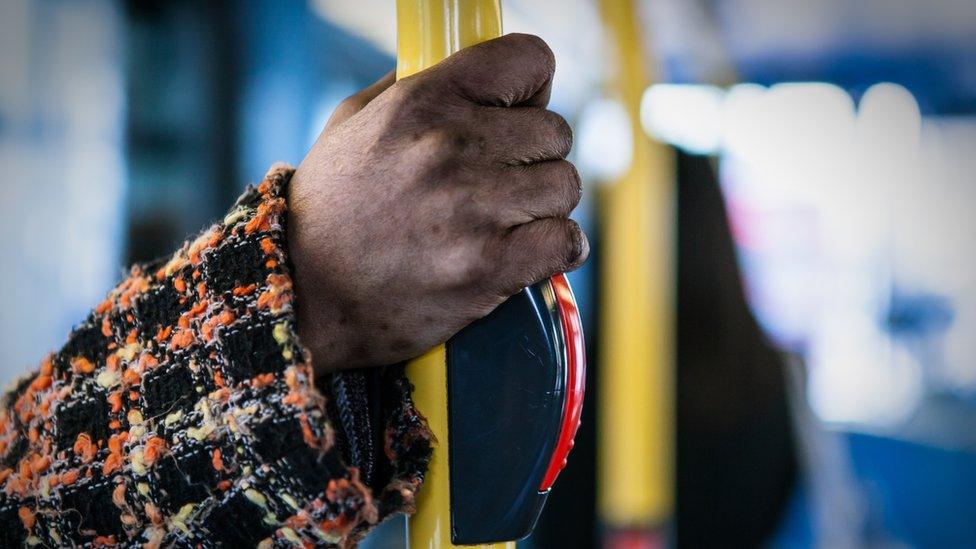 A passenger holds a handrail on a train