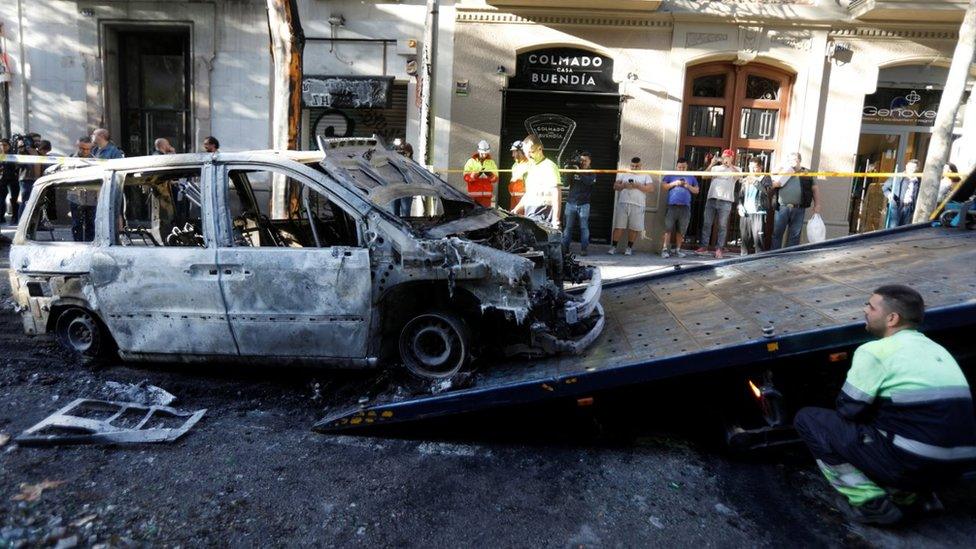 A worker removes a burned car after clashes of separatist demonstrators after a verdict in a trial over a banned independence referendum in Barcelona, Spain, October 17,