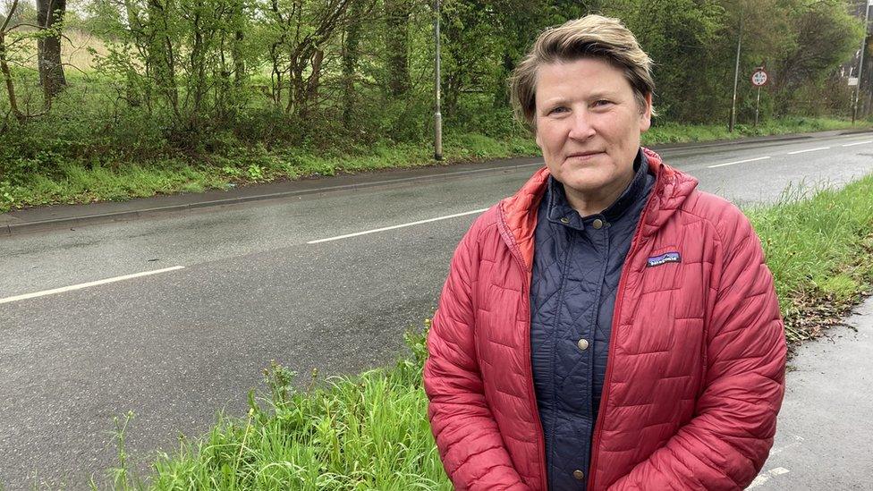 Sarah Dyke standing next to a main road, wearing a red jacket