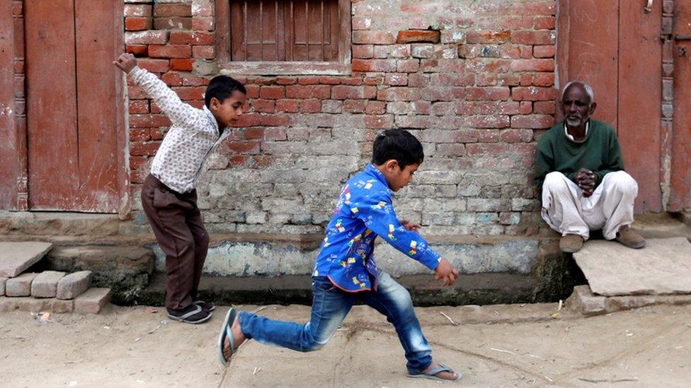 Children play as a man sits outside a house in Nayabans village in Bulandshahr district, Uttar Pradesh, India. 5 December 2018.