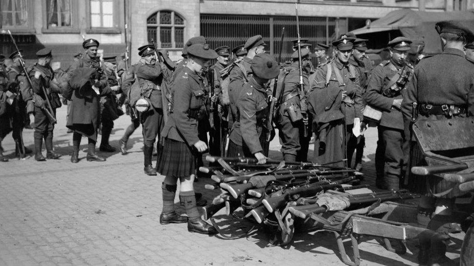 Group of soldiers piling rifles up on the ground in a French square